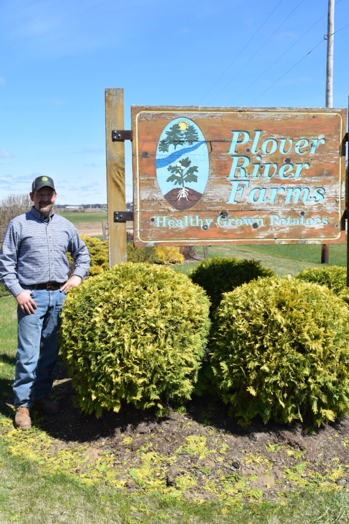 Randy Fleishauer in front of sign for Plover River Farms